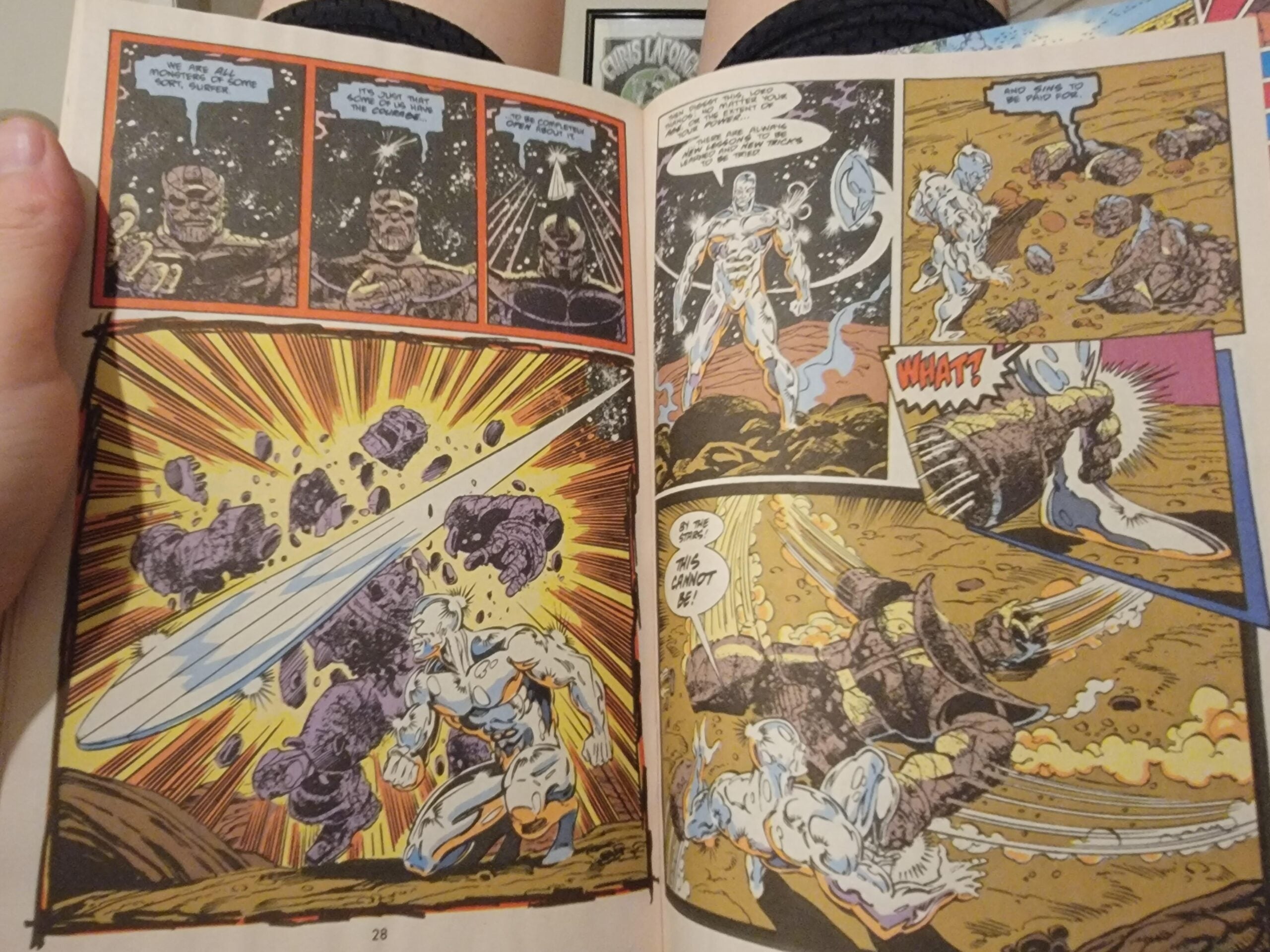 A person holds an open comic book showing an action scene with Silver Surfer fighting a large rocky villain amid cosmic backgrounds and explosive effects.