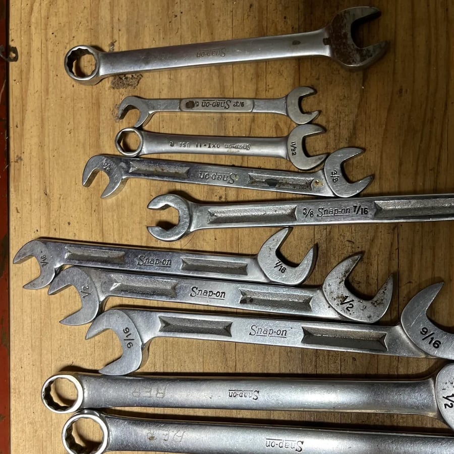 A set of Snap-on wrenches in various sizes is arranged on a wooden surface, with some wrenches overlapping each other.