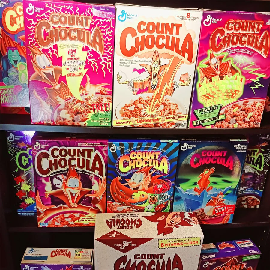 A display shelf filled with various colorful boxes of Count Chocula cereal, showing different designs and cartoon vampire mascots from over the years.