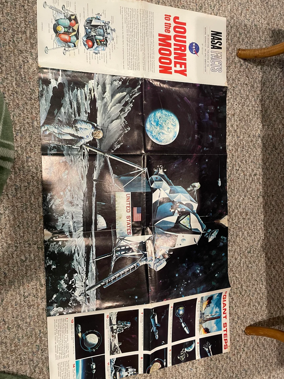 A vintage NASA poster titled “Journey to the Moon” with illustrations of an astronaut, lunar module, Earth, and comic-strip style panels showing steps of the Apollo mission. The poster is laid out on a carpeted floor.