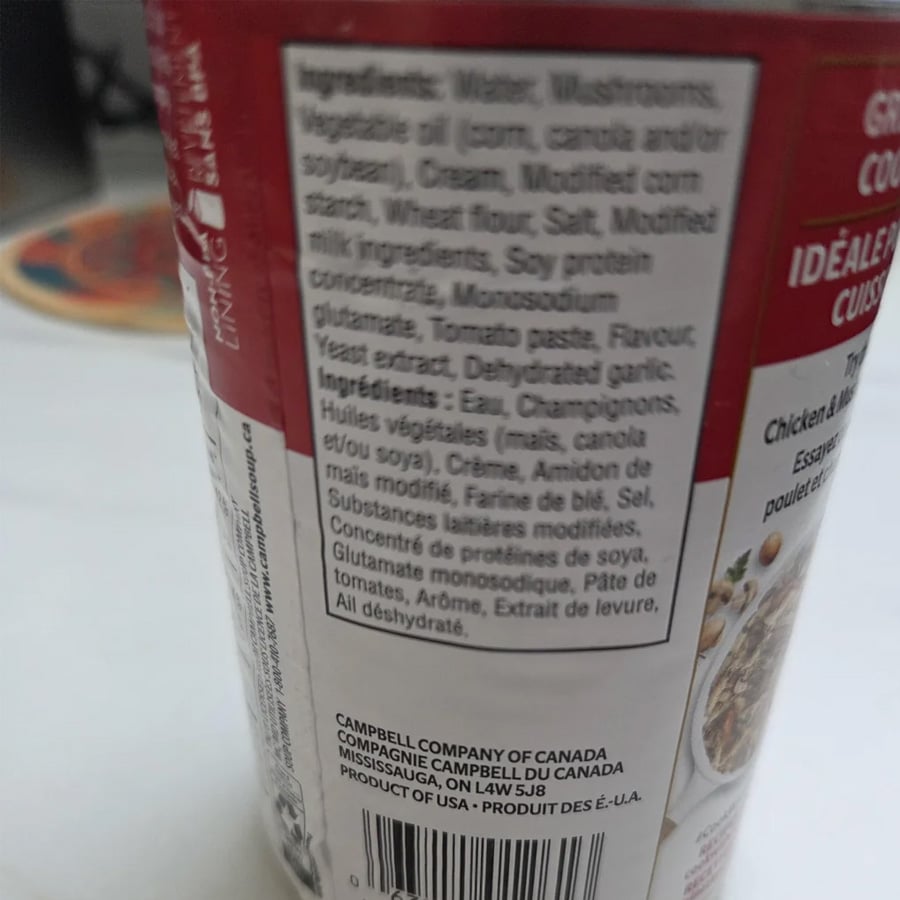 A close-up of a soup can label showing the ingredients list, including water, mushrooms, concentrated soups, wheat flour, salt, modified milk ingredients, and more. The text is in both English and French.