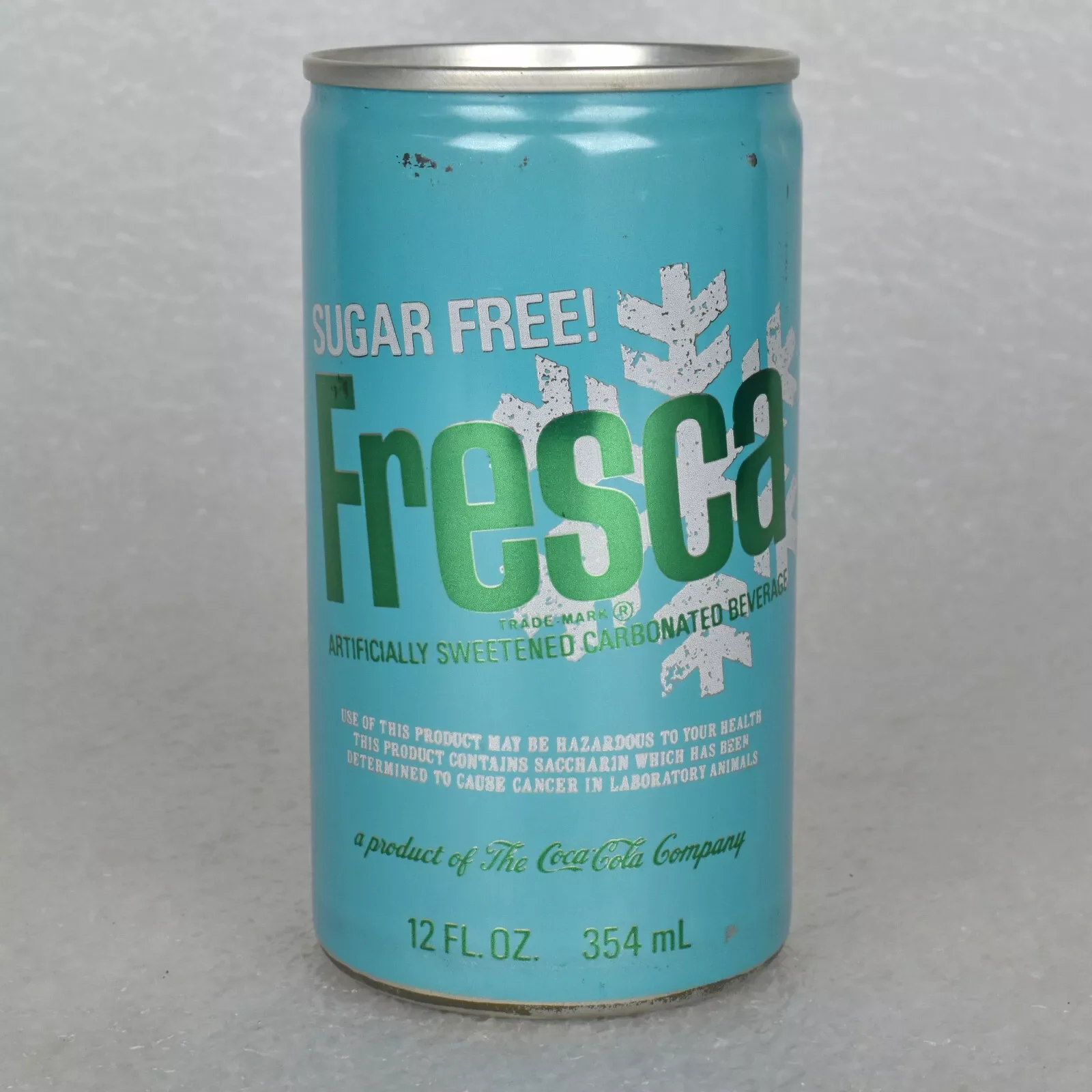 A blue can of sugar-free Fresca, an artificially sweetened carbonated beverage, with a white snowflake design and product warnings. The can holds 12 fl. oz. and is made by The Coca-Cola Company.