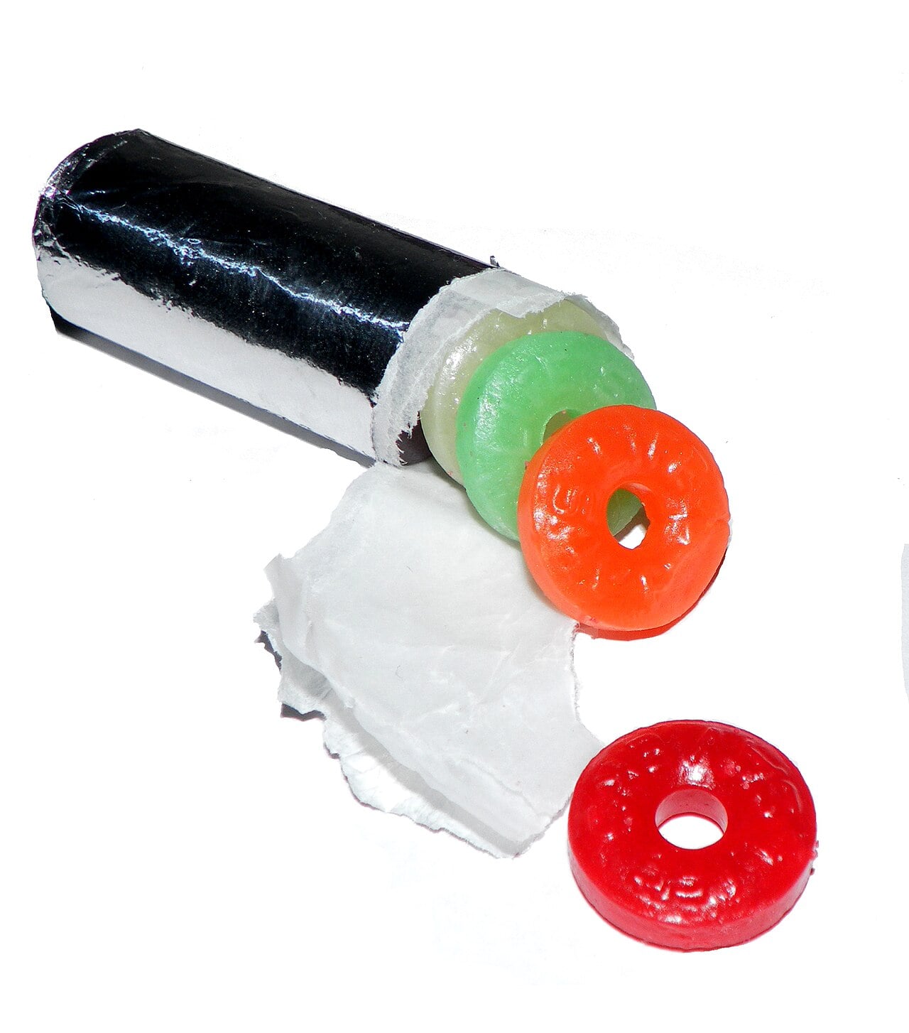 A roll of colorful ring-shaped hard candies, partly unwrapped from silver foil, with green, orange, and red candies visible.