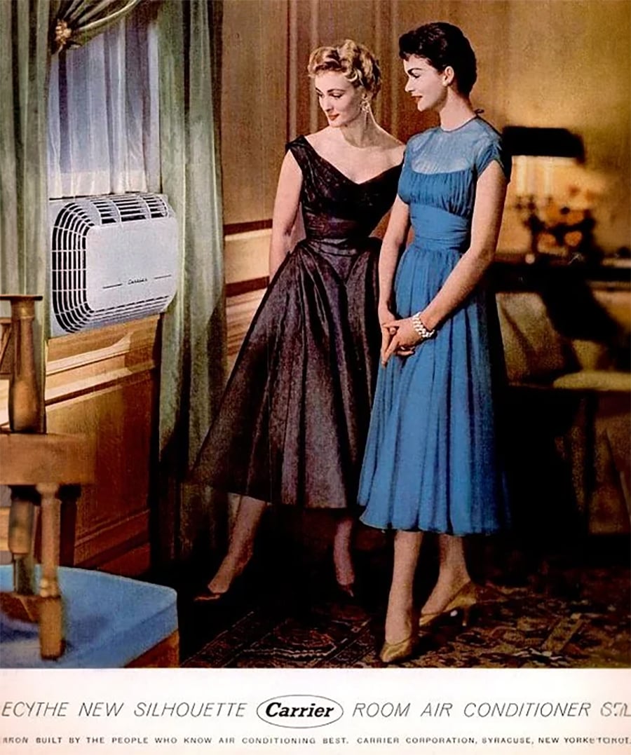 Two women in elegant 1950s dresses admire a wall-mounted air conditioner in a vintage living room. One woman wears black, the other blue. A green curtain and wooden furniture are visible.