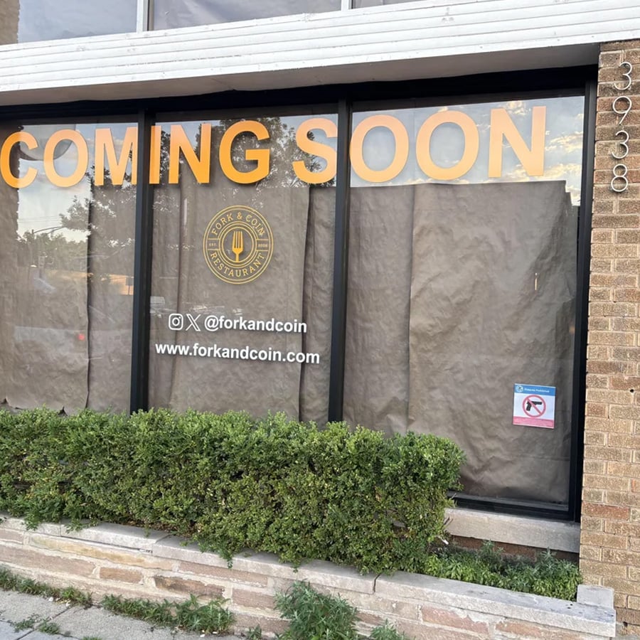 Restaurant windows covered in paper with “COMING SOON” and “Fork & Coin” logo. Social media handle and website are visible. No smoking sign on door. Bushes line the front. Address number 3938 on the right.