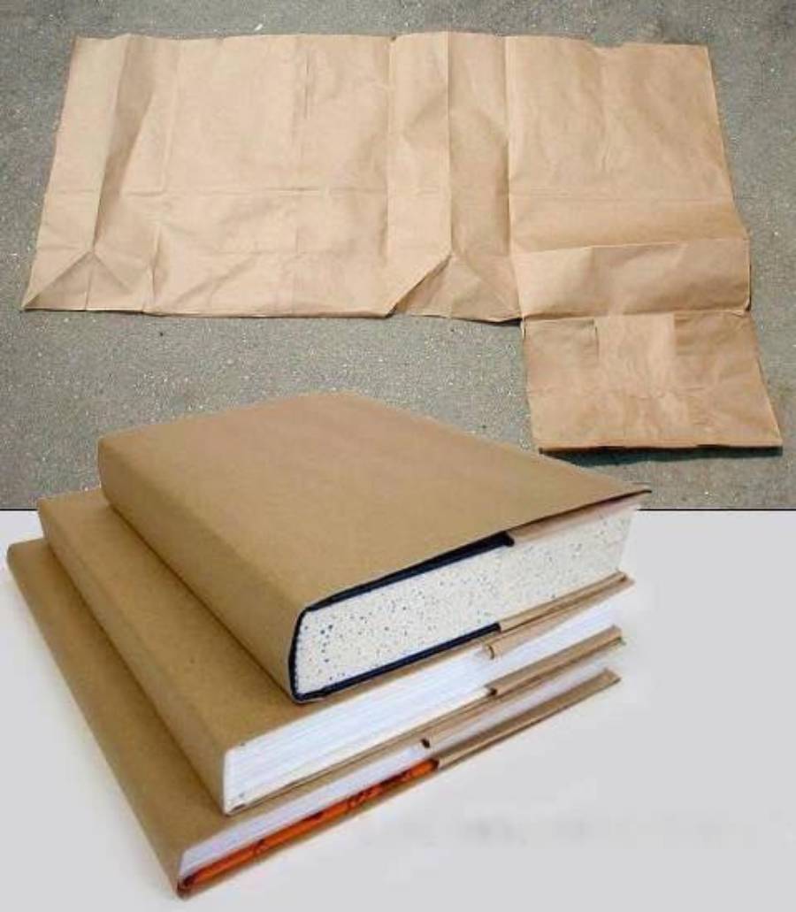 Three books are covered with plain brown paper. Above them, sheets of brown paper are laid out flat on a gray surface, ready to be folded into book covers.
