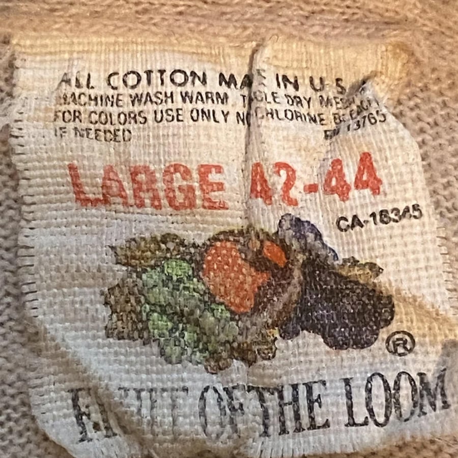 A worn Fruit of the Loom clothing tag showing “LARGE 42-44,” wash instructions, and a faded fruit logo.