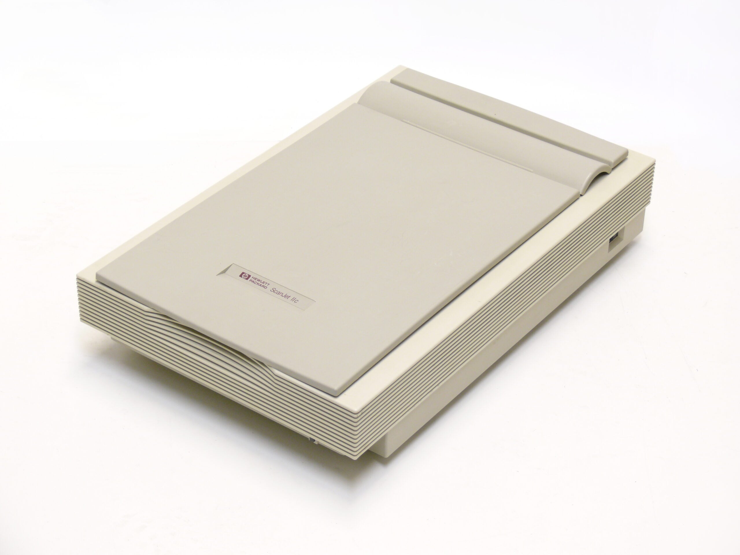 A beige flatbed scanner with a slanted lid and vented sides, placed on a white background. The HP ScanJet Plus logo is visible on the top.