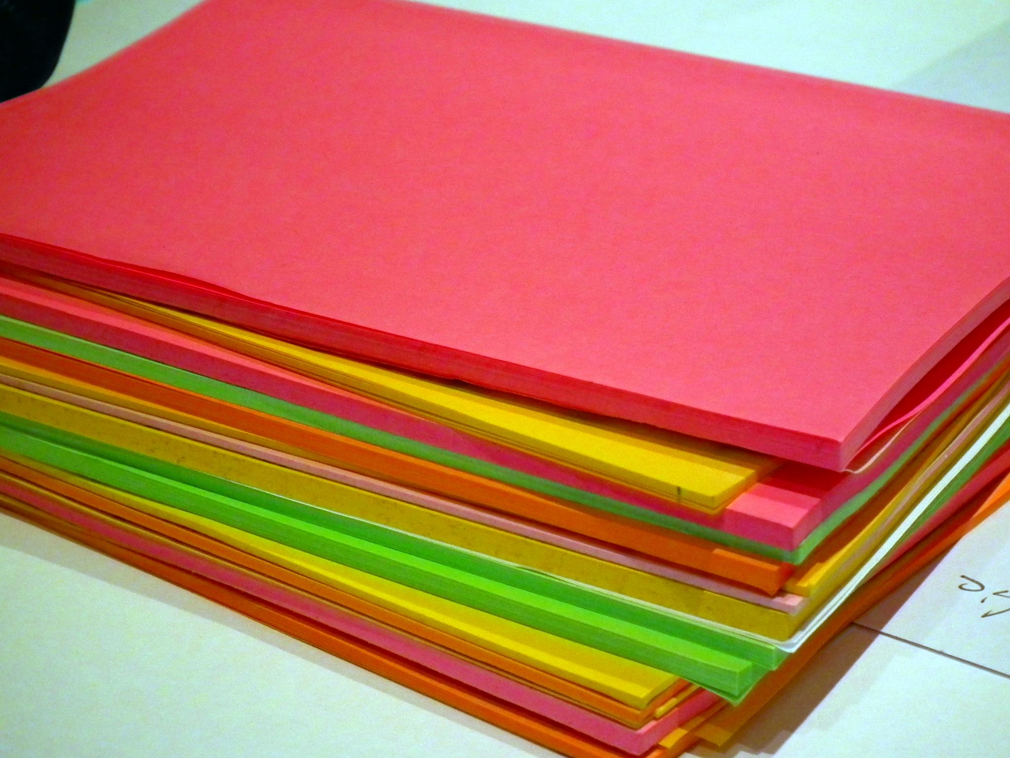 A stack of multicolored paper sheets in shades of red, yellow, orange, and green.