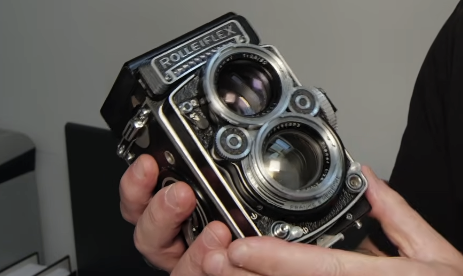 A person holding a Rolleiflex twin-lens reflex camera.