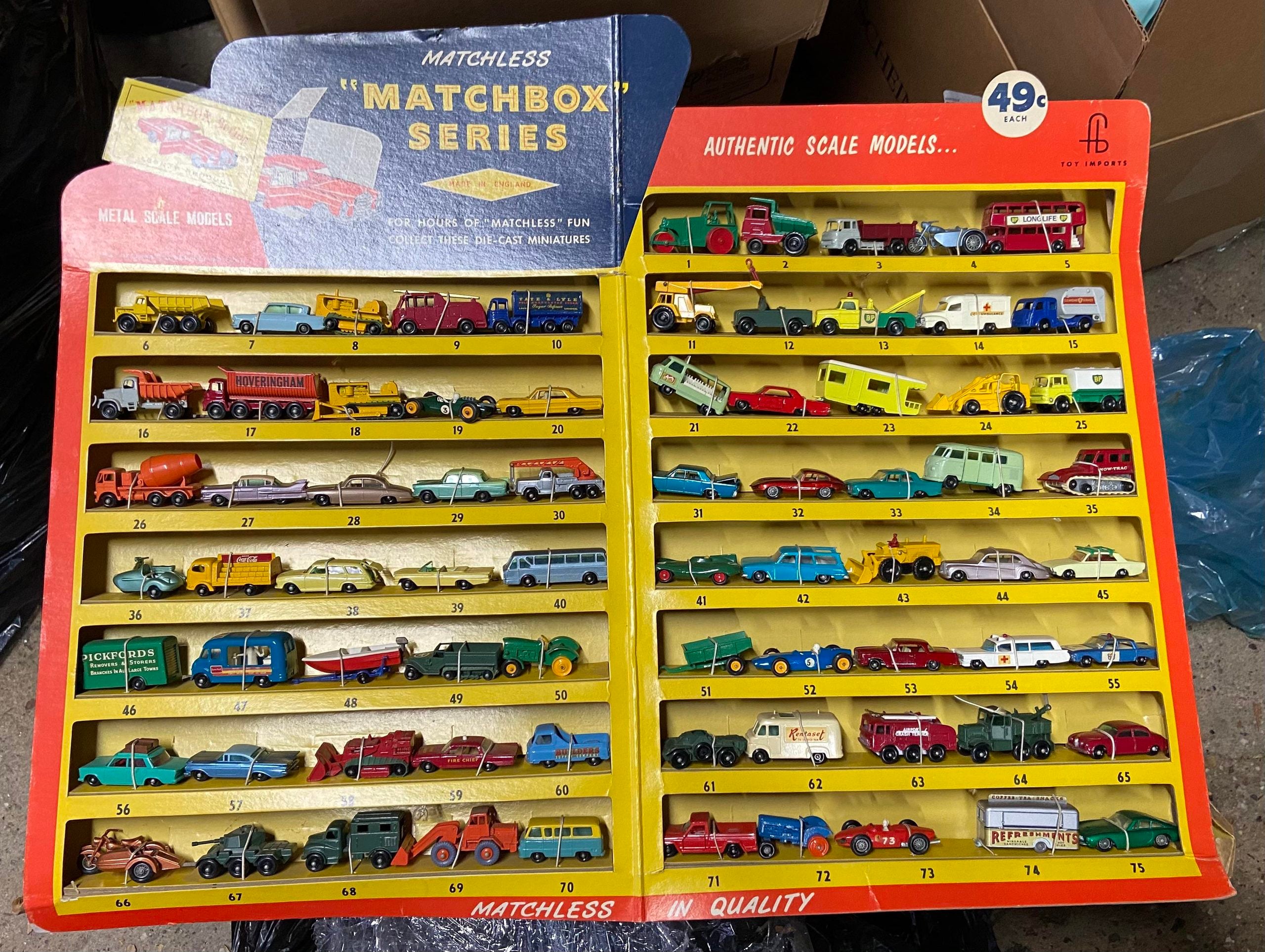 Display board for Matchbox Series die-cast toy vehicles, featuring 75 numbered slots filled with various miniature cars, trucks, and trailers.