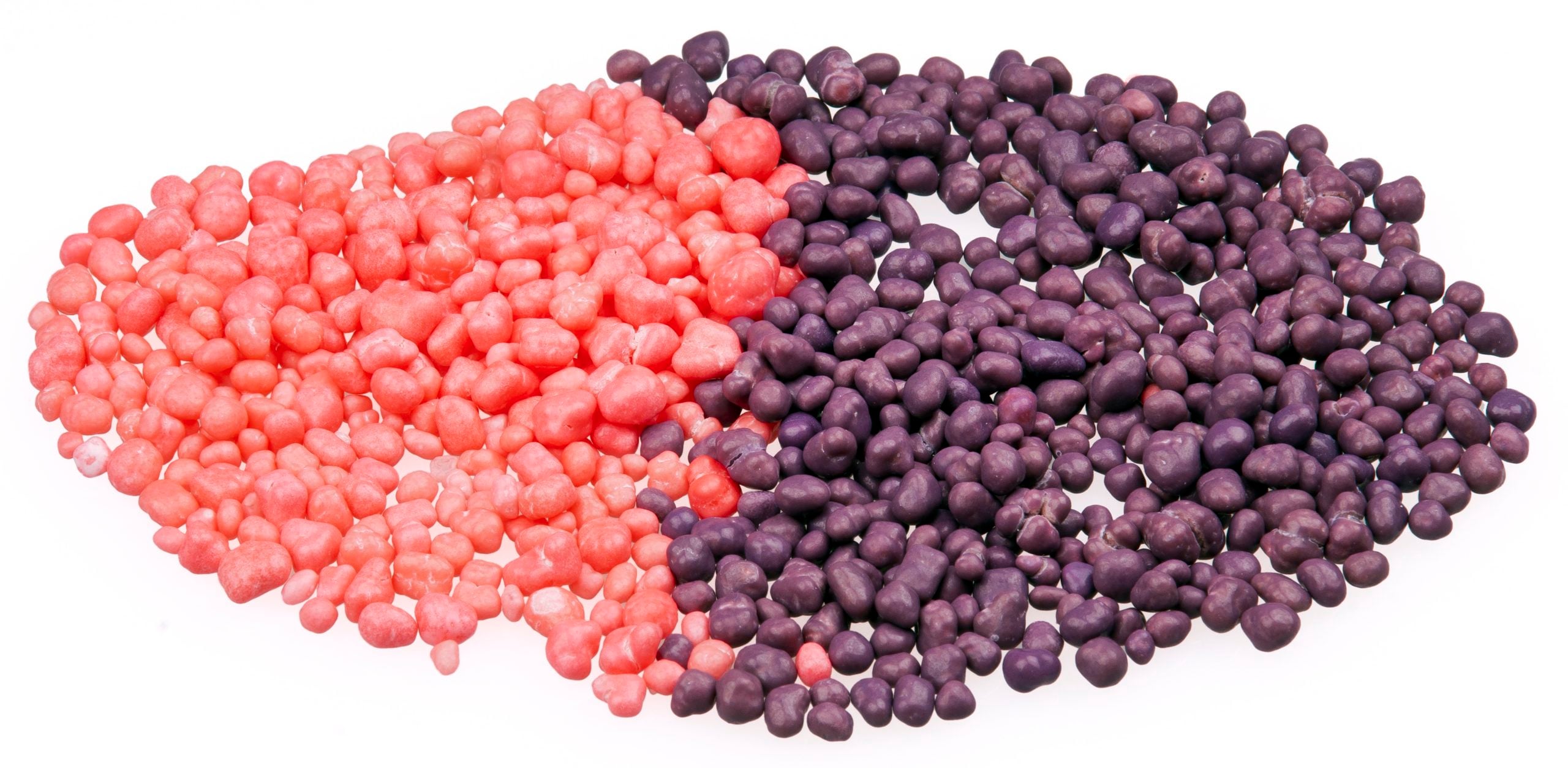 A pile of small, round, candy-coated sweets divided into pink and purple sections.