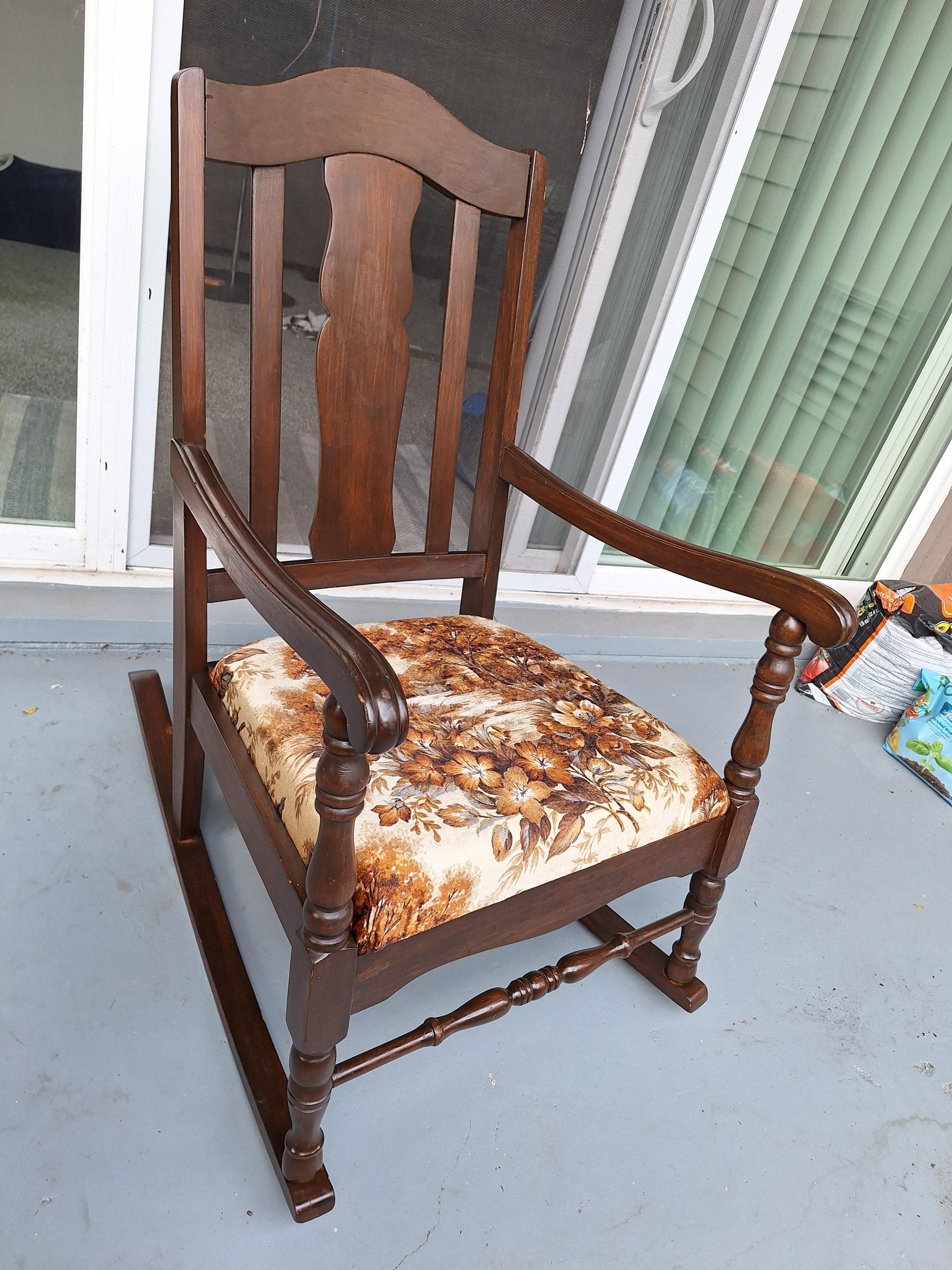 Dark wood rocking chair with a floral print seat cushion.