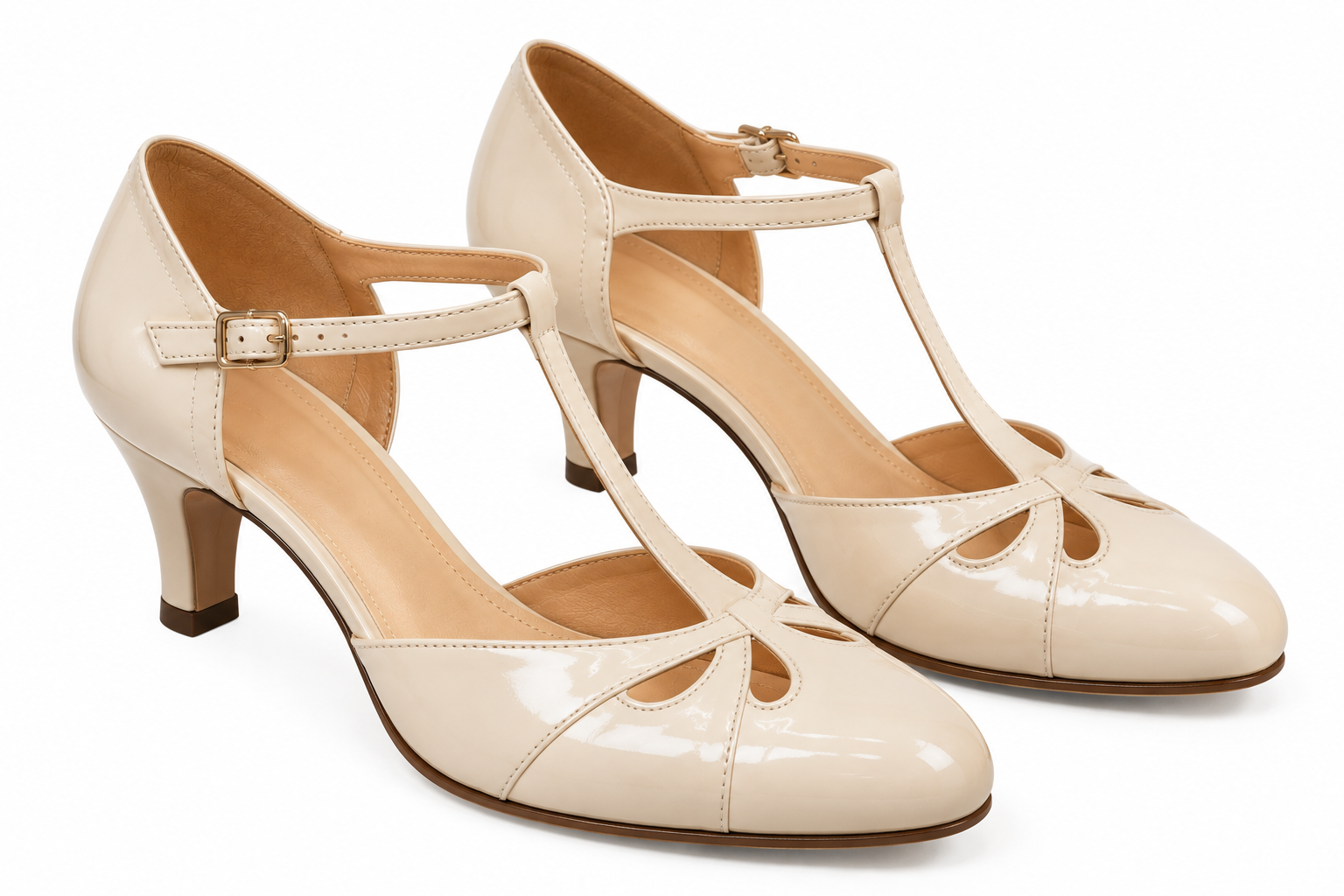 Pair of beige t-strap heels with a round toe and low kitten heel.