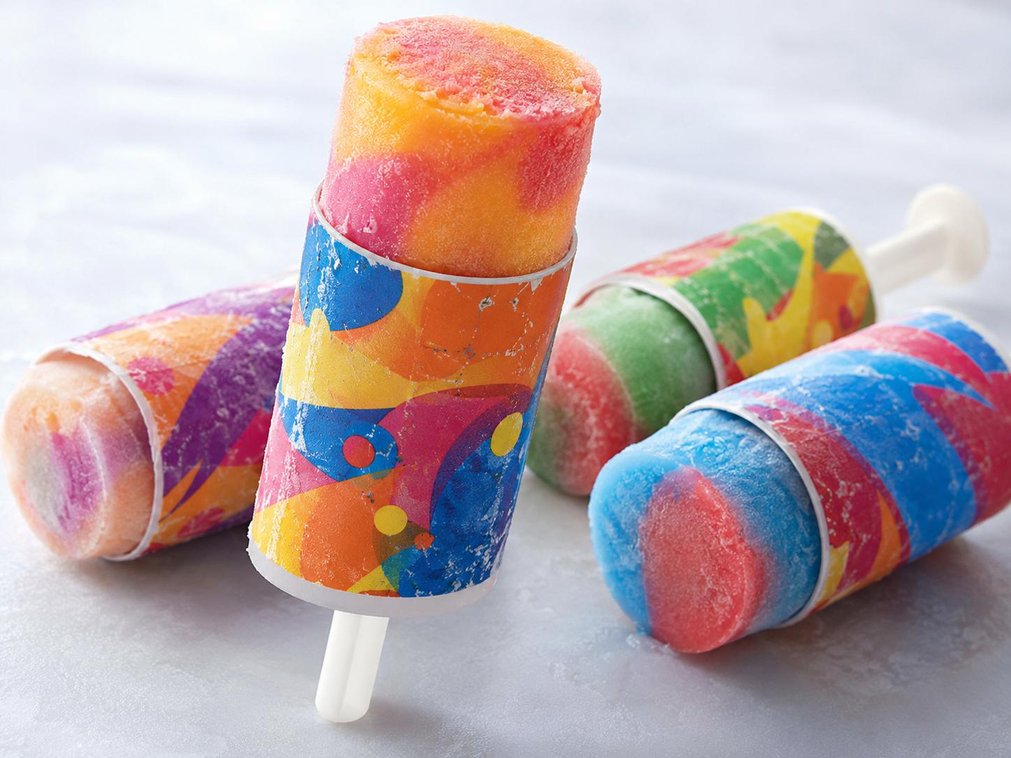 Four colorful, swirl-patterned ice pops in push-up wrappers.