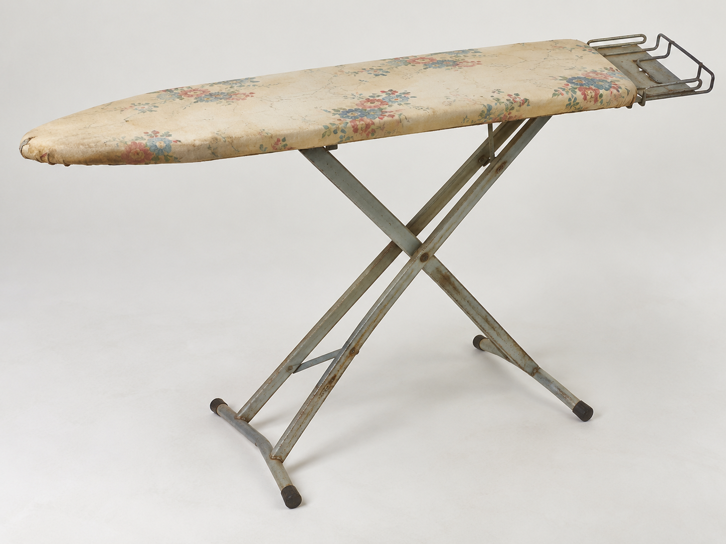 An ironing board with a floral patterned cover and a metal iron rest.
