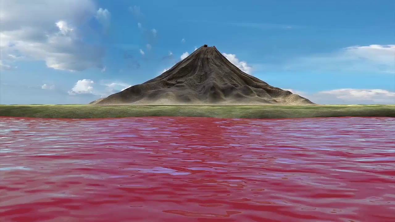 A conical mountain rising above a grassy plain beside a body of red water under a blue sky.