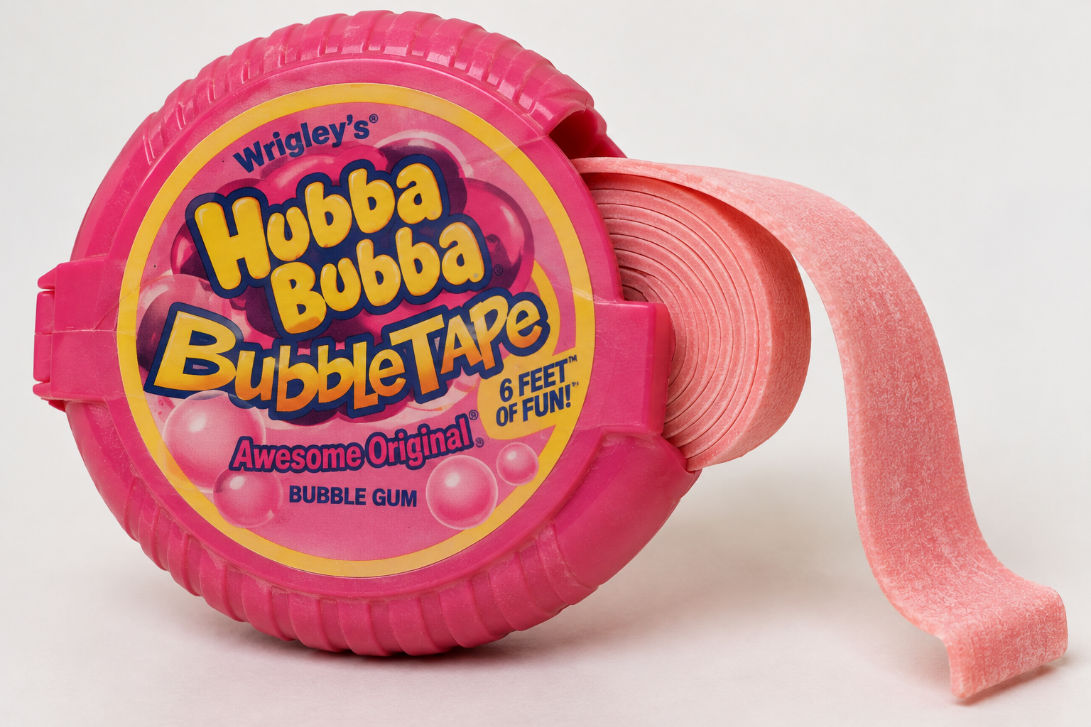A round, pink plastic dispenser of Hubba Bubba Bubble Tape with a strip of pink bubble gum unspooled to the right.
