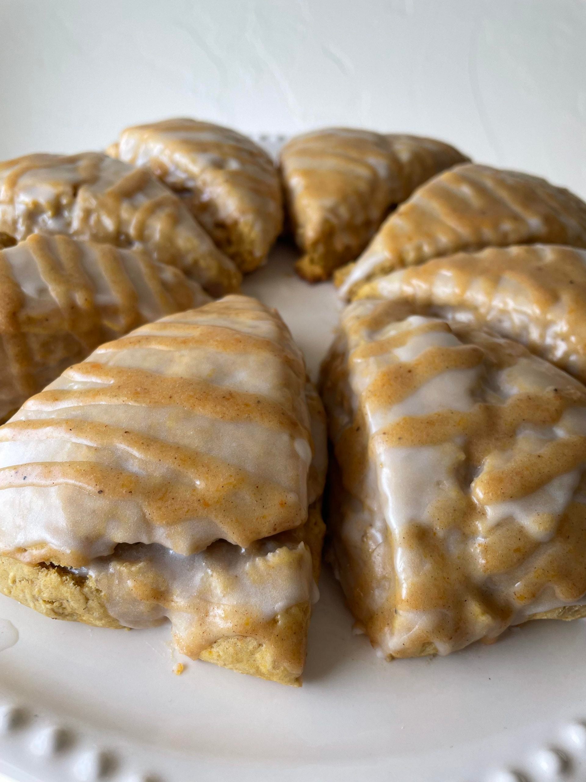 A circle of triangular scones drizzled with white and tan icing on a white plate.