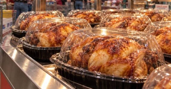 Rows of rotisserie chickens in plastic containers under a Costco sign labeled 4.99.