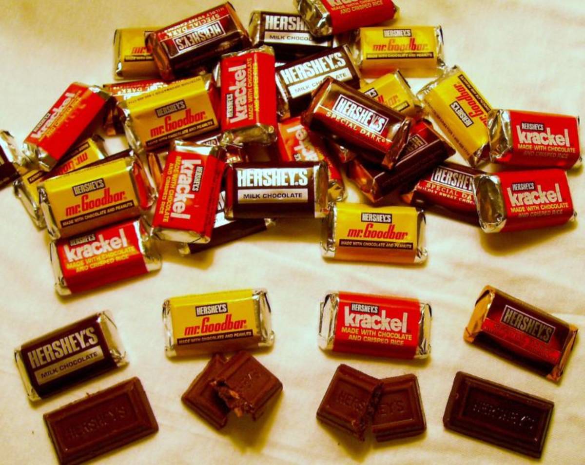 A pile of assorted Hershey’s miniature chocolate bars, including Milk Chocolate, Mr. Goodbar, Krackel, and Special Dark, with four unwrapped pieces in the foreground.