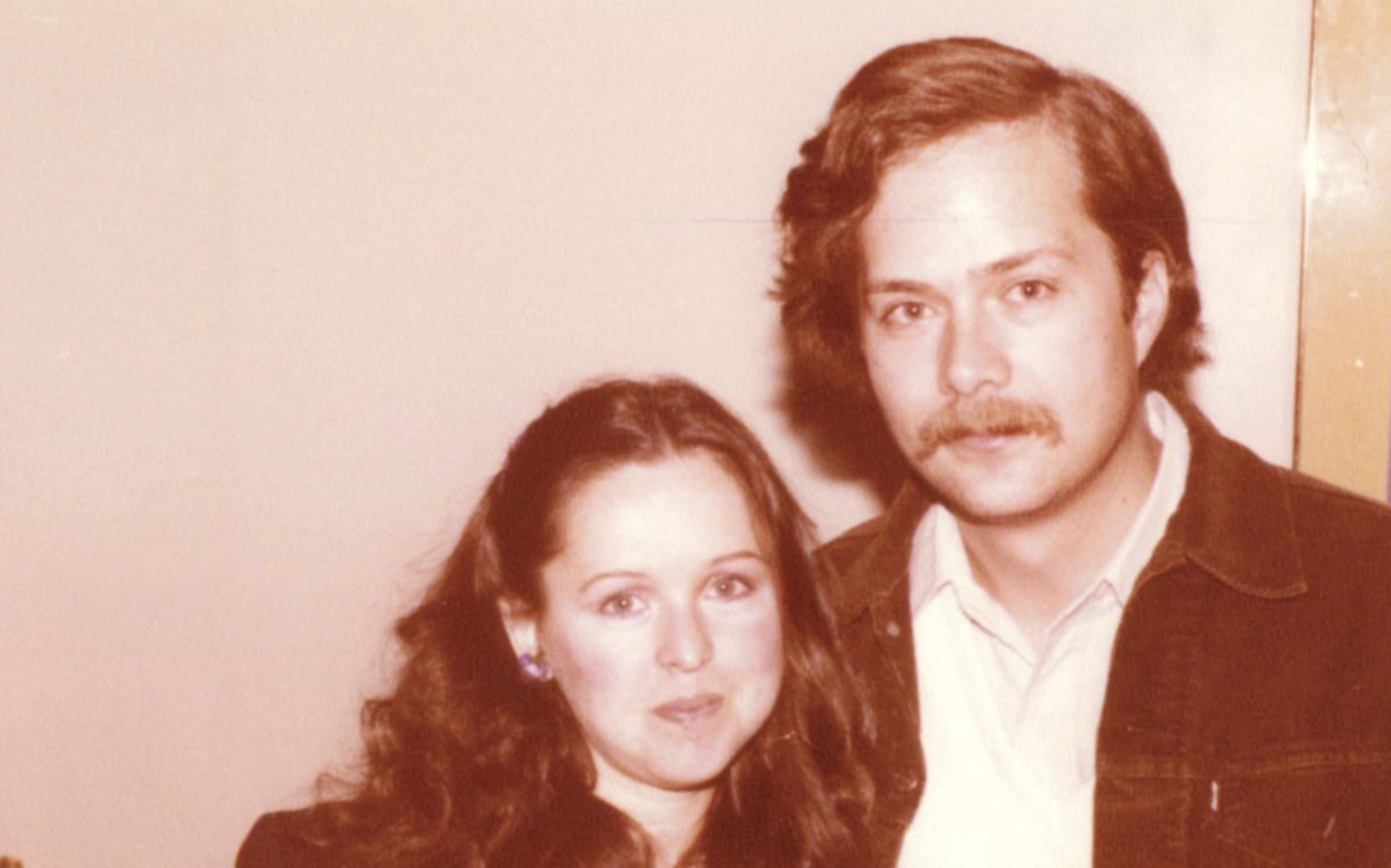 A man with a mustache and a woman with long dark hair posing for a portrait.