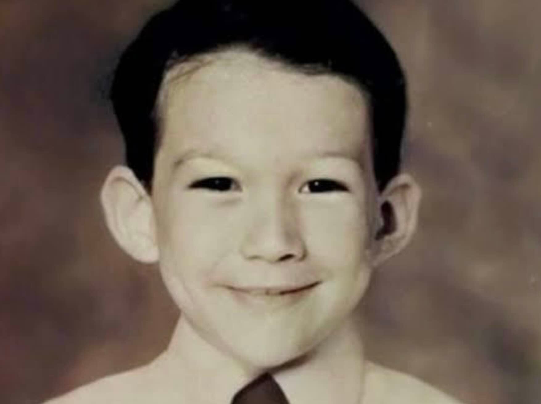 A vintage portrait of a young boy smiling.