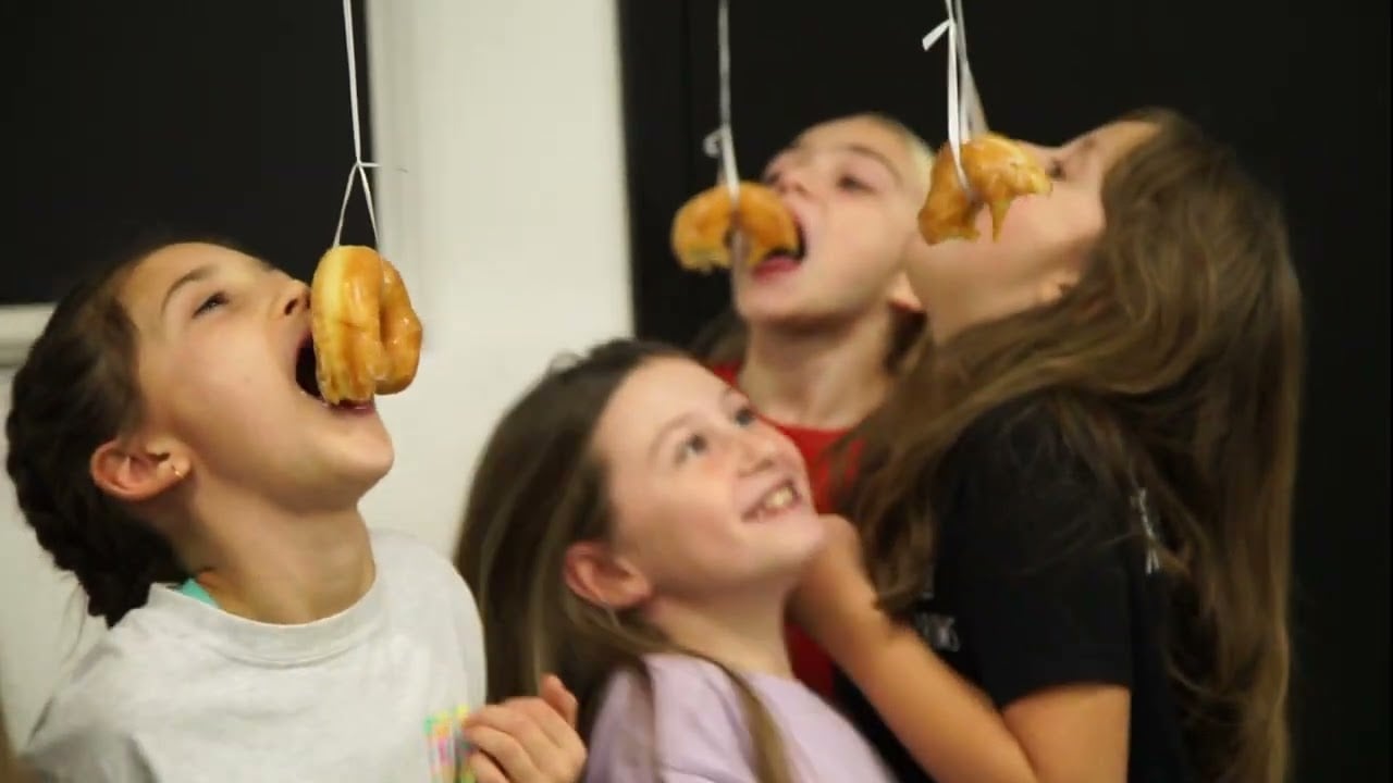 Four children competing in a donut-on-a-string eating game.