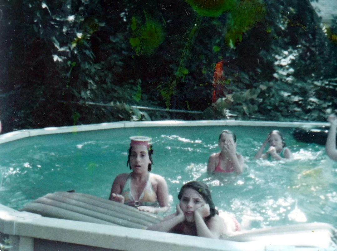 Four children play in a backyard swimming pool.