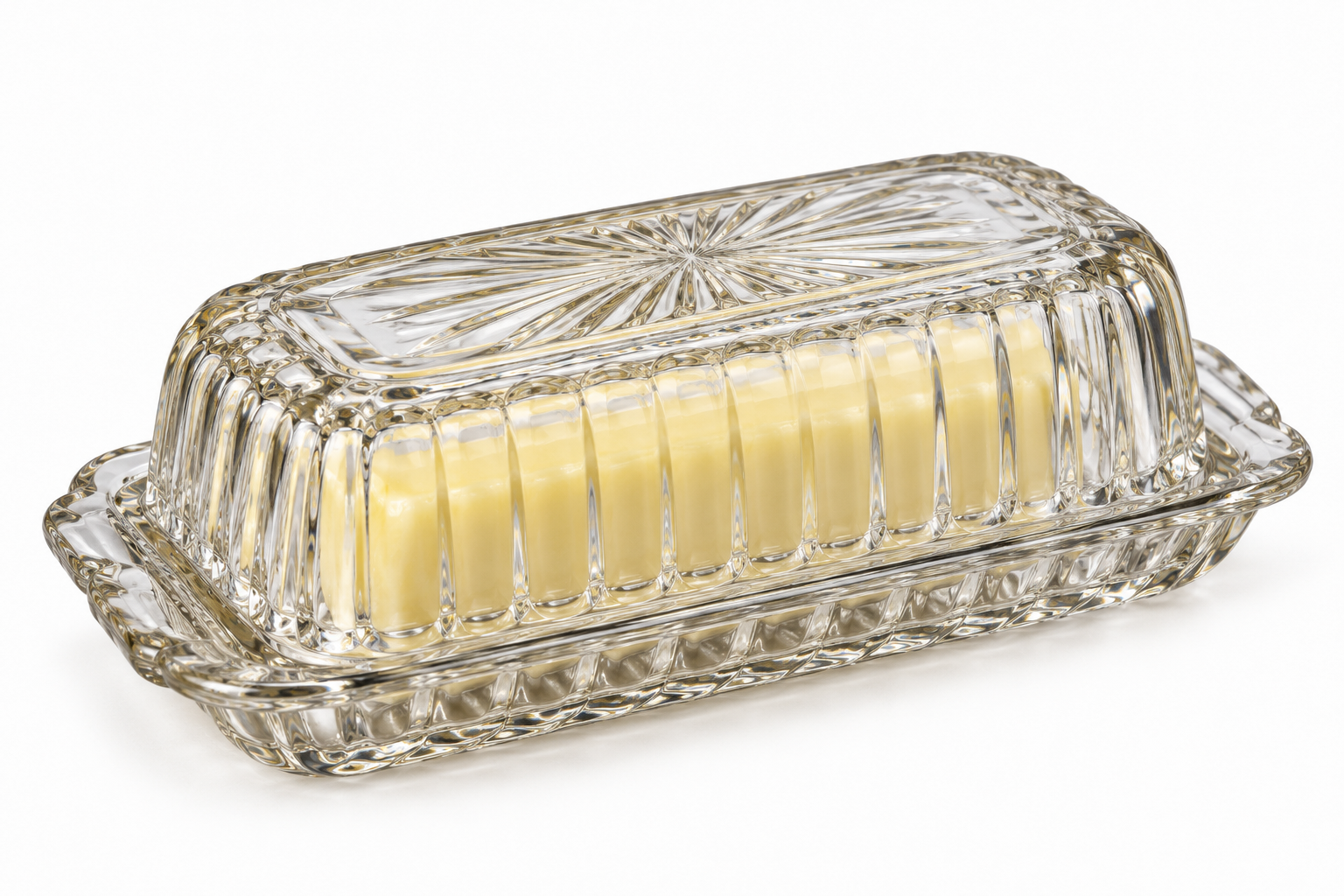 A block of butter inside a lidded, decorative glass butter dish.