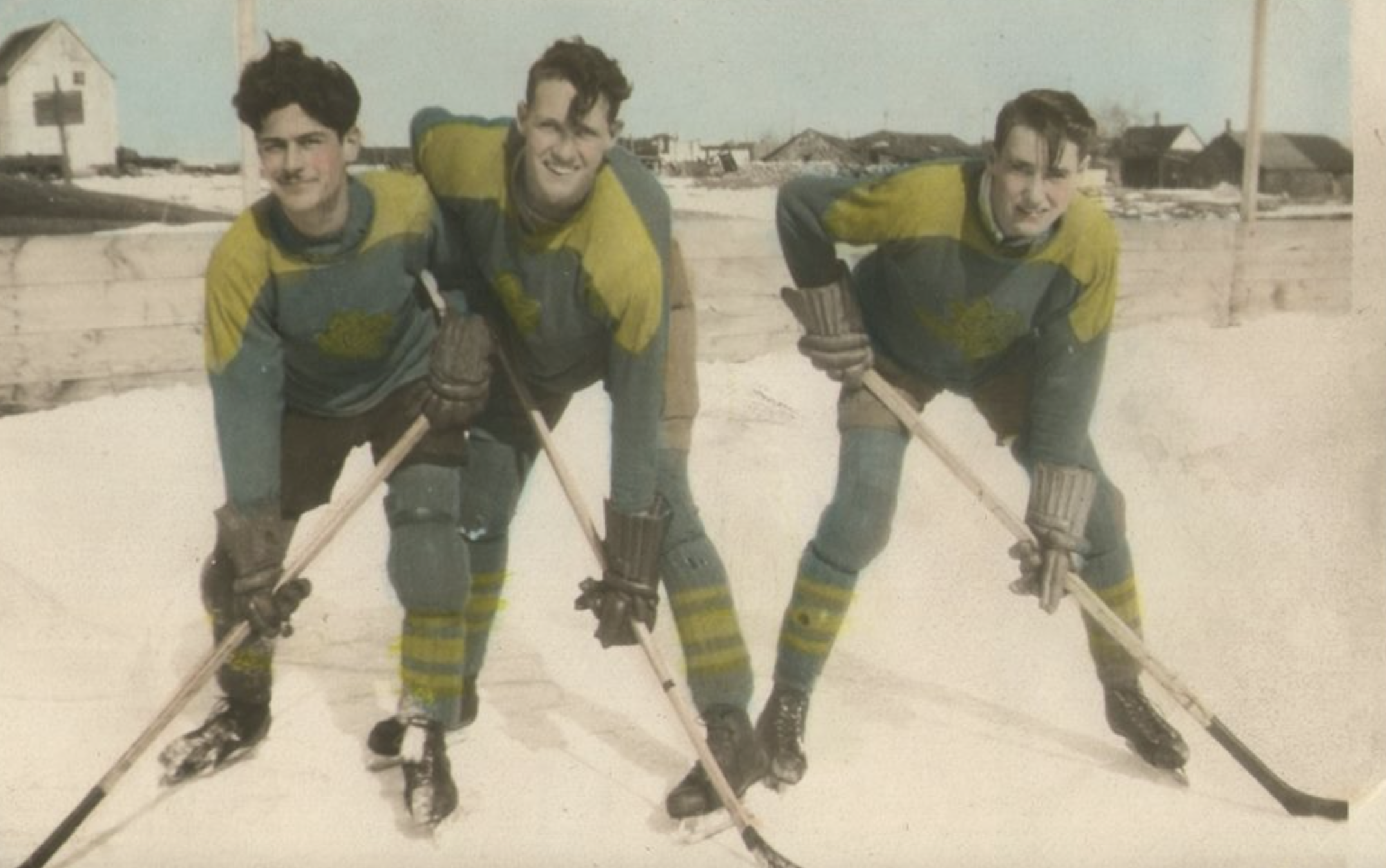 Three hockey players in vintage sweaters and skates posed on an outdoor ice rink.