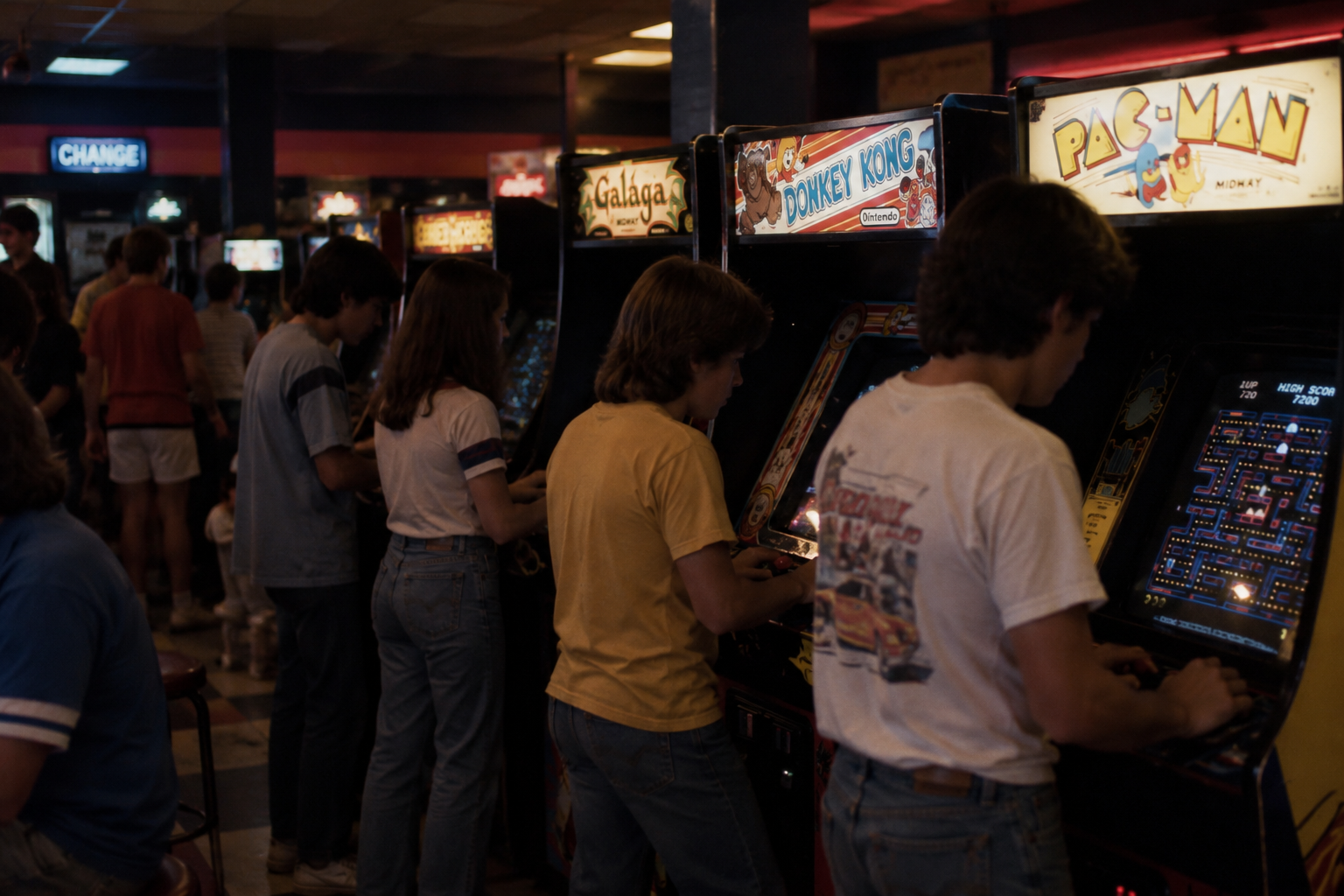 Several teenagers play vintage arcade games including Donkey Kong and Pac-Man in a dimly lit arcade.