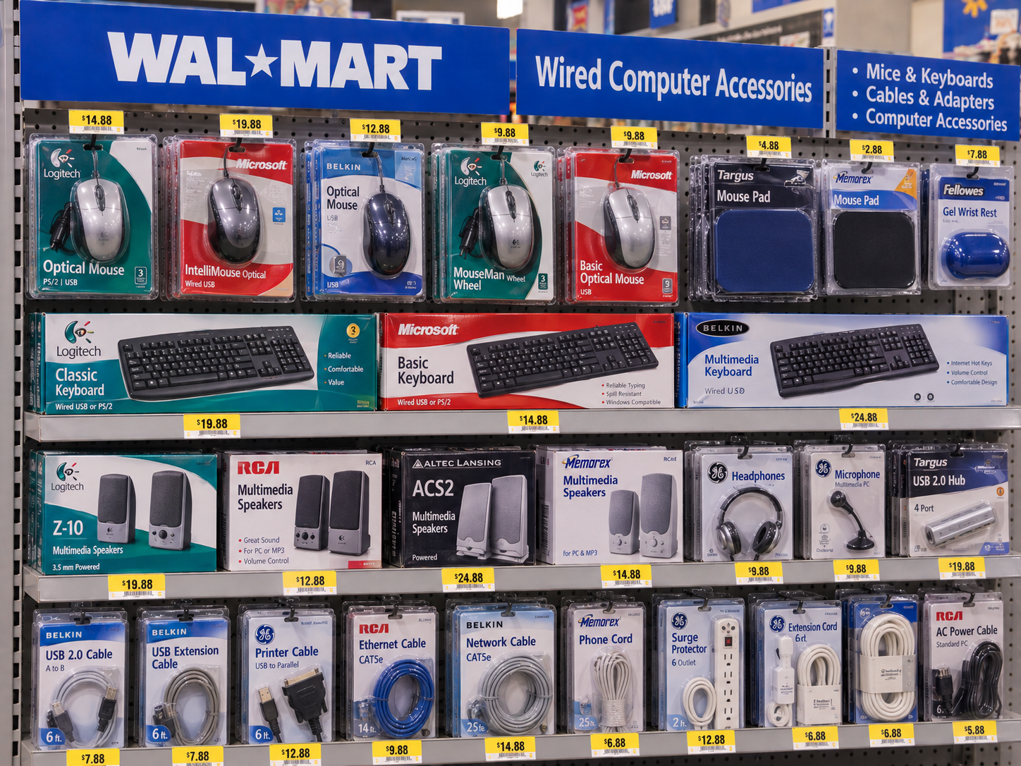 Retail shelf display of various computer peripherals and accessories including mice, keyboards, speakers, and cables, with price tags for each item.