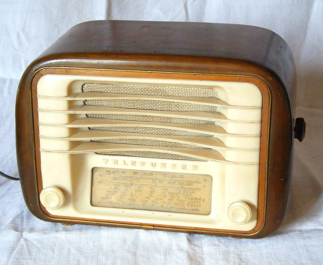 Vintage Telefunken tabletop radio with a wood cabinet, cream-colored speaker grille, and manual tuning dial.