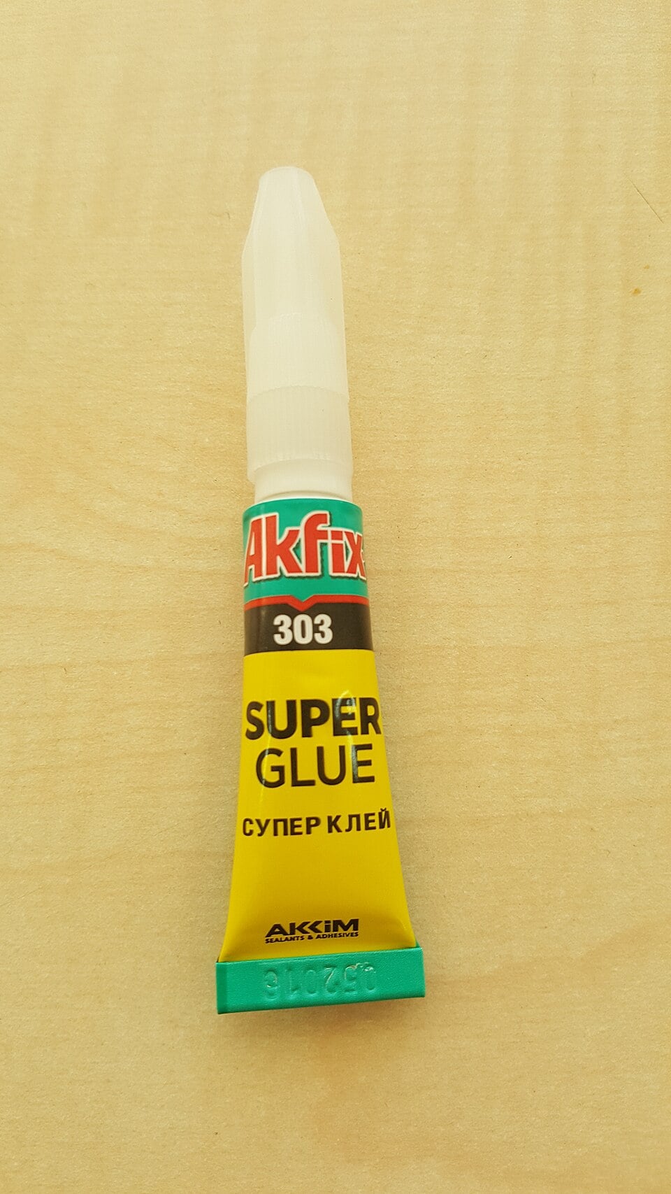 A tube of Akfix 303 super glue with a white cap.