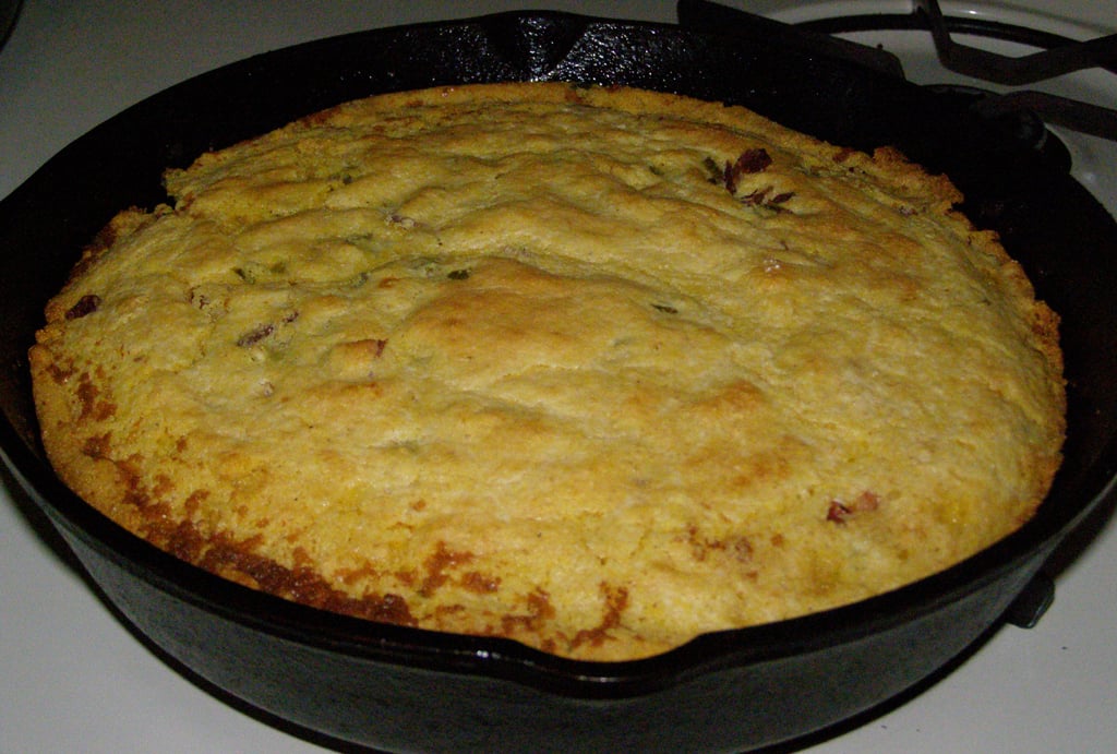 Golden brown cornbread baked in a black cast iron skillet, resting on a stovetop.