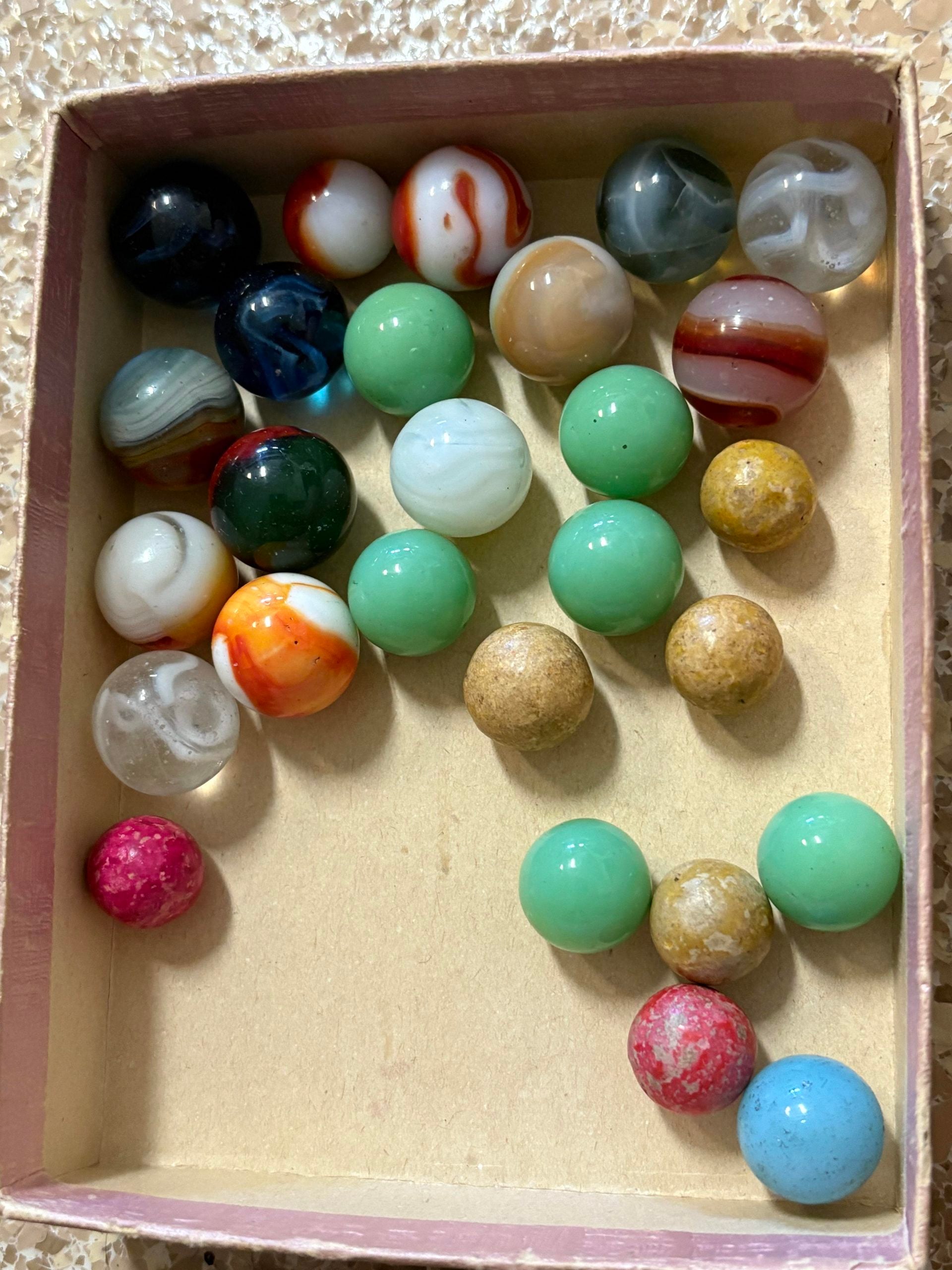 A collection of colorful glass marbles in a cardboard box.