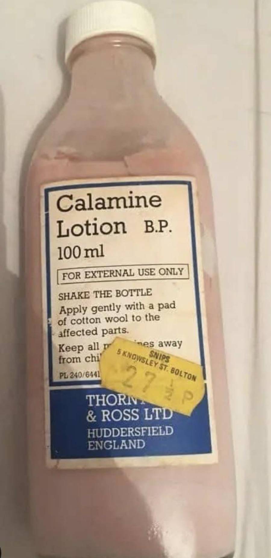 A bottle of pink calamine lotion with a label reading “Calamine Lotion B.P. 100ml” and a price sticker showing “27 1/2 p.”