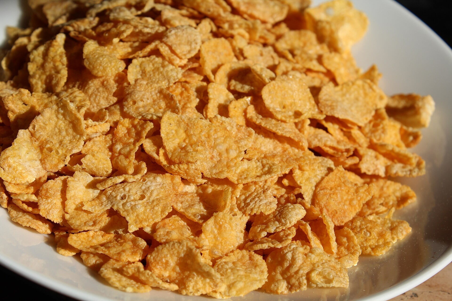 A white bowl filled with golden cornflakes.