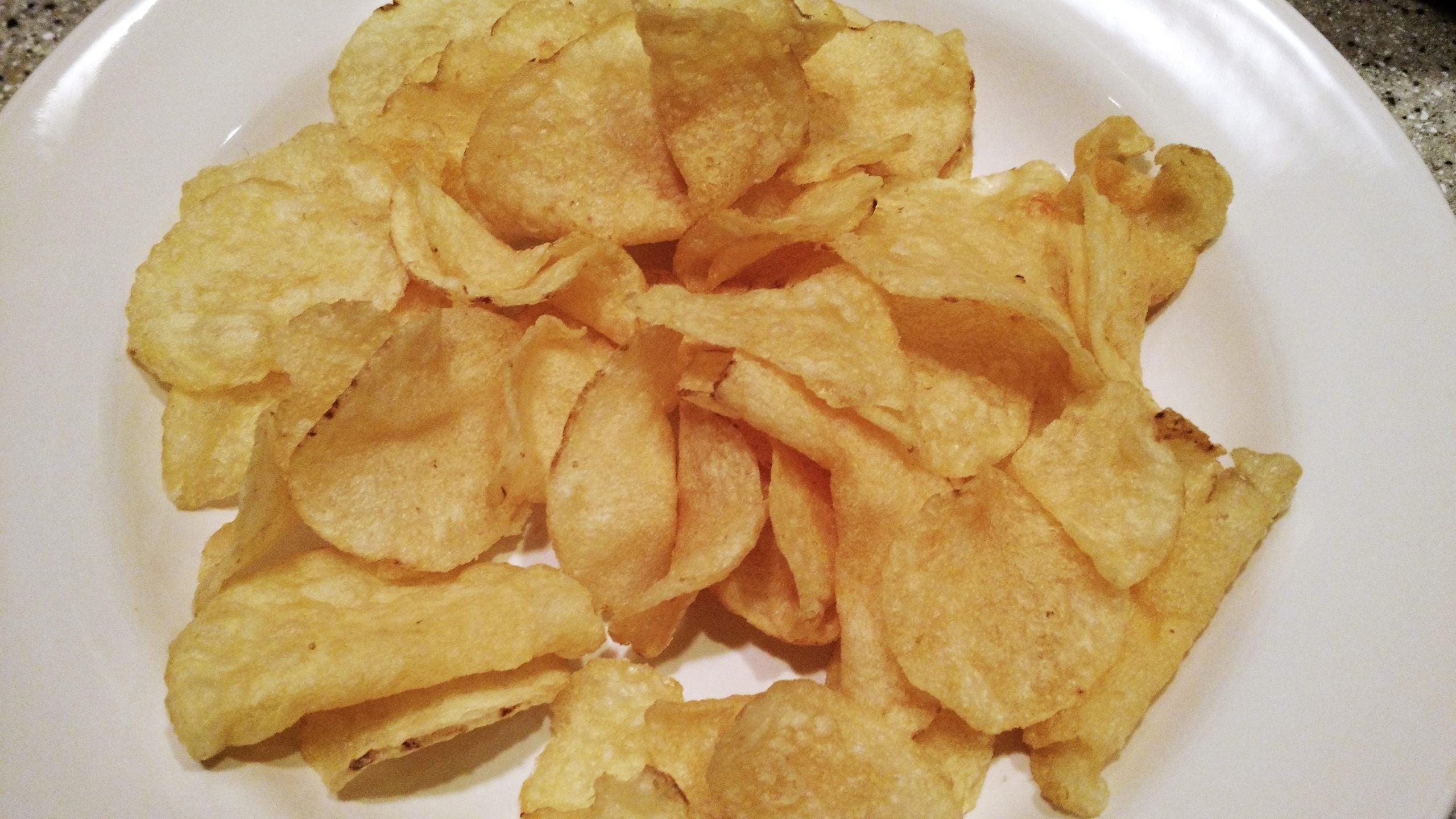 A white plate piled with potato chips.