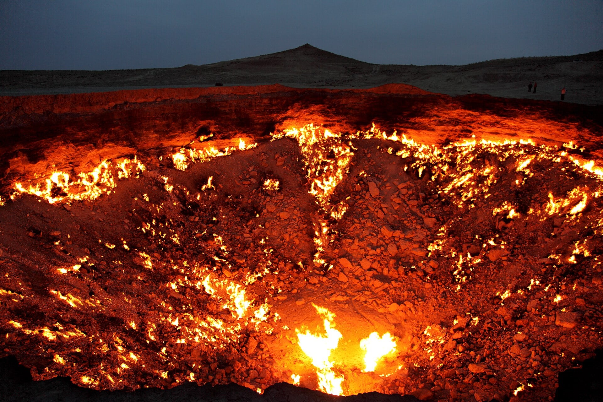 The Darvaza gas crater, a large pit in the desert floor filled with burning flames.