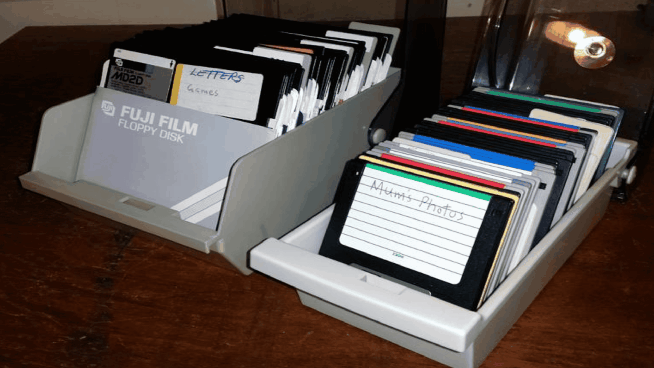 Two storage trays filled with 3.5-inch floppy disks, some labeled with handwritten text like “Letters” and “Mum’s Photos.”