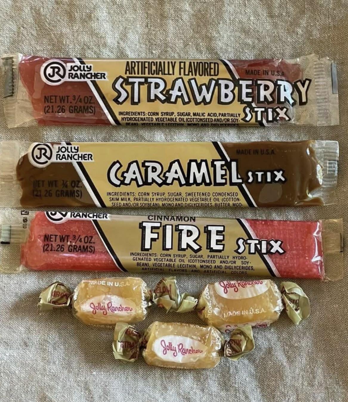 Three Jolly Rancher candy sticks in strawberry, caramel, and cinnamon flavors, with three wrapped Jolly Rancher candies below.