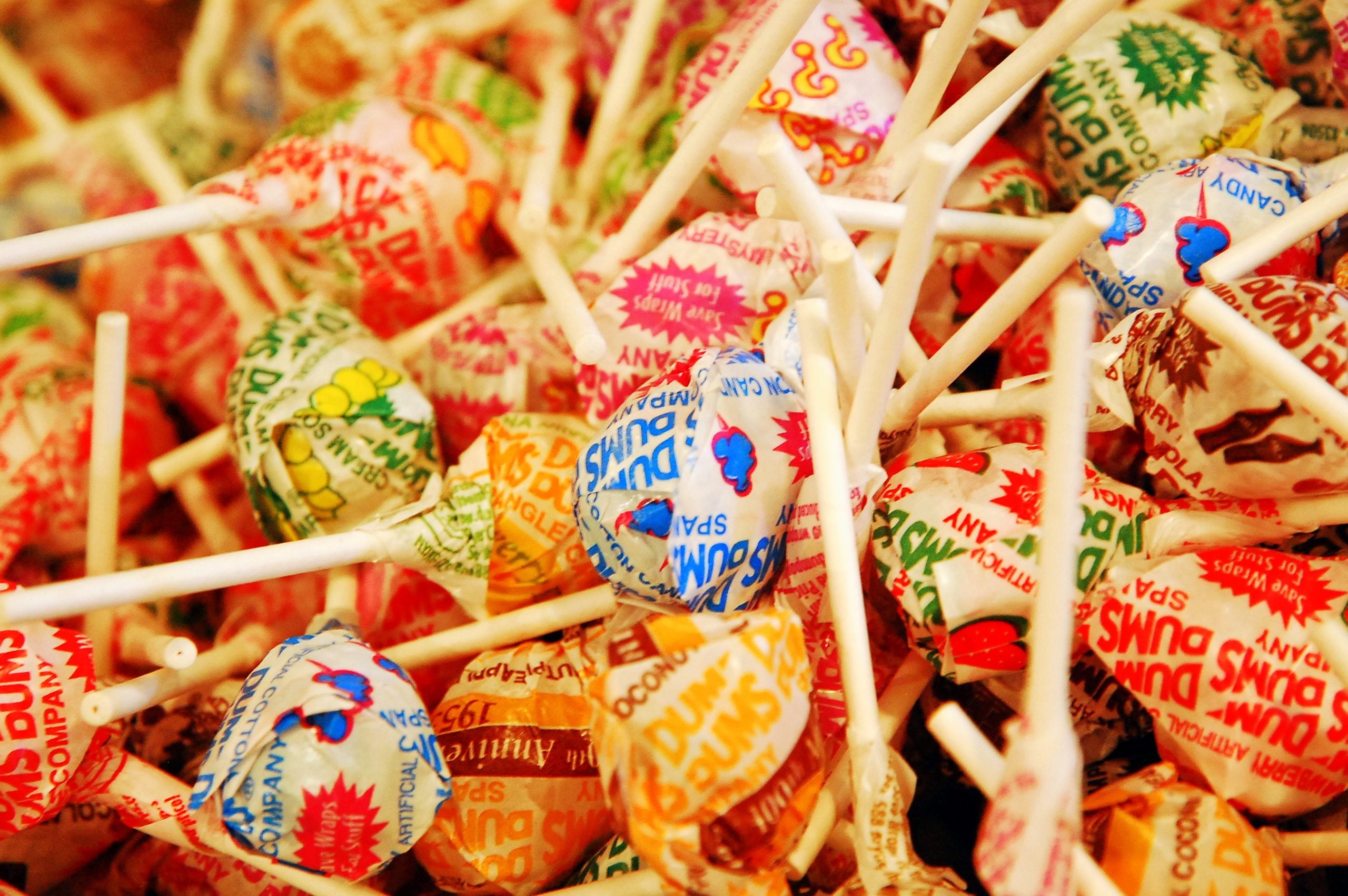 A pile of assorted Dum Dums lollipops in various colorful wrappers.