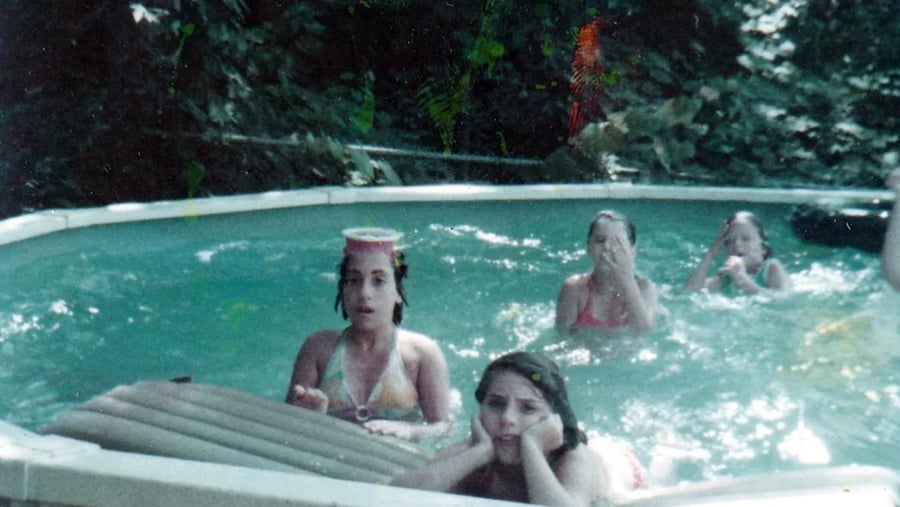 Four girls playing in an above-ground swimming pool.