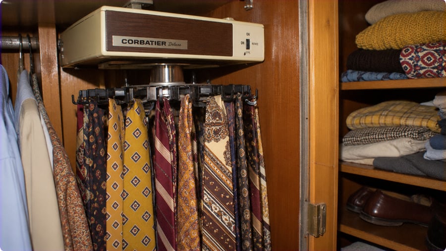 An electric rotating tie rack mounted in a closet, holding a collection of patterned neckties.