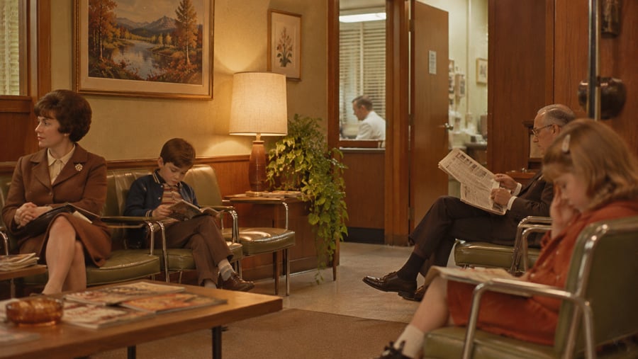 People sitting in a waiting room with retro decor, reading books and newspapers.