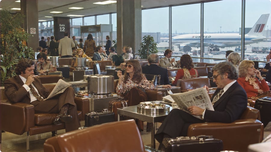 Passengers wait in an airport gate lounge with views of a United Airlines jet parked on the tarmac.