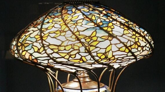 Stained glass lamp with a dome-shaped shade featuring a web-like pattern of yellow and blue glass pieces.
