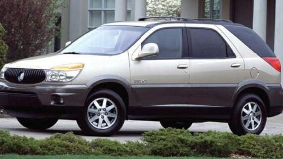 A two-tone tan and dark gray Buick Rendezvous SUV parked in a driveway.